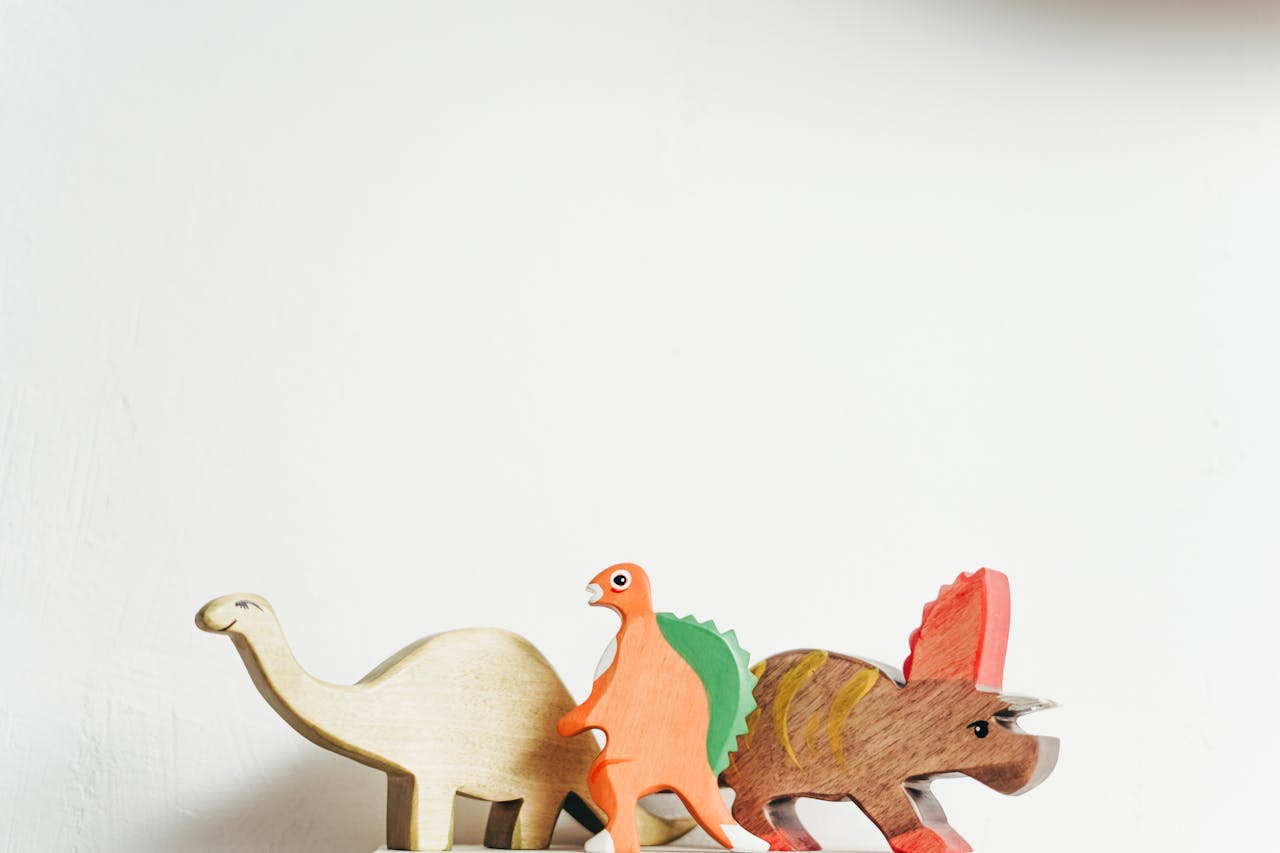 Three wooden dinosaur toys on a white background showcasing playful creativity.
